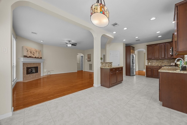 kitchen featuring visible vents, ceiling fan, arched walkways, a sink, and open floor plan
