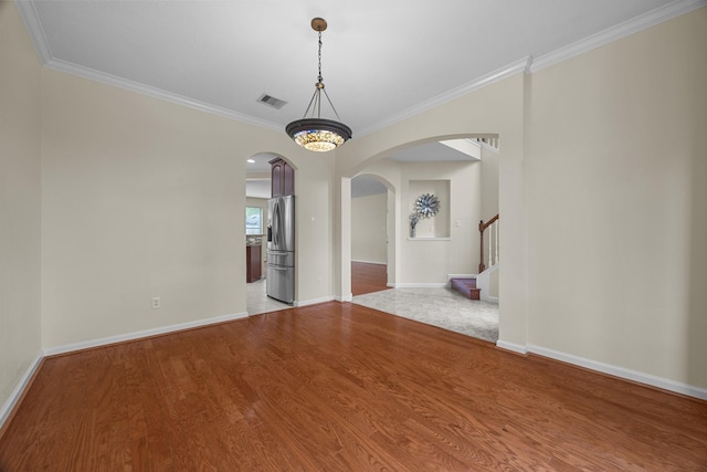 unfurnished room with arched walkways, baseboards, visible vents, and wood finished floors