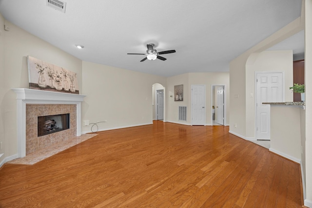 unfurnished living room with a ceiling fan, light wood-style flooring, arched walkways, and visible vents