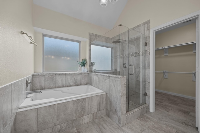 full bathroom with a garden tub, vaulted ceiling, a walk in closet, and a shower stall