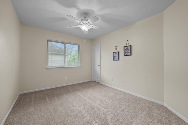 empty room with baseboards, carpet floors, ceiling fan, and a textured ceiling