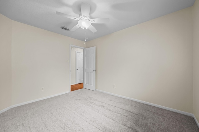 carpeted empty room with a ceiling fan, baseboards, and visible vents