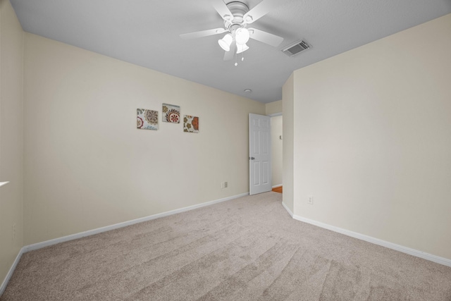spare room with visible vents, baseboards, light colored carpet, and ceiling fan