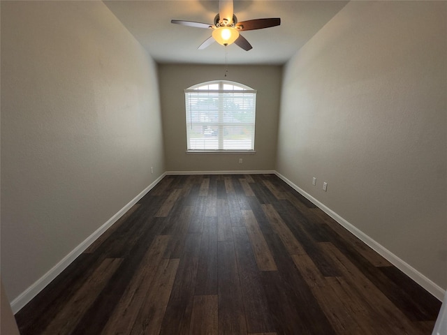 spare room featuring baseboards, dark wood-type flooring, and a ceiling fan