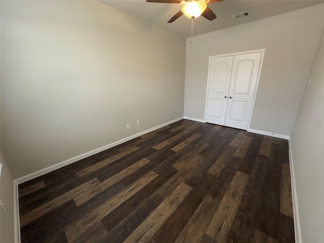 unfurnished bedroom featuring ceiling fan, visible vents, baseboards, and dark wood finished floors