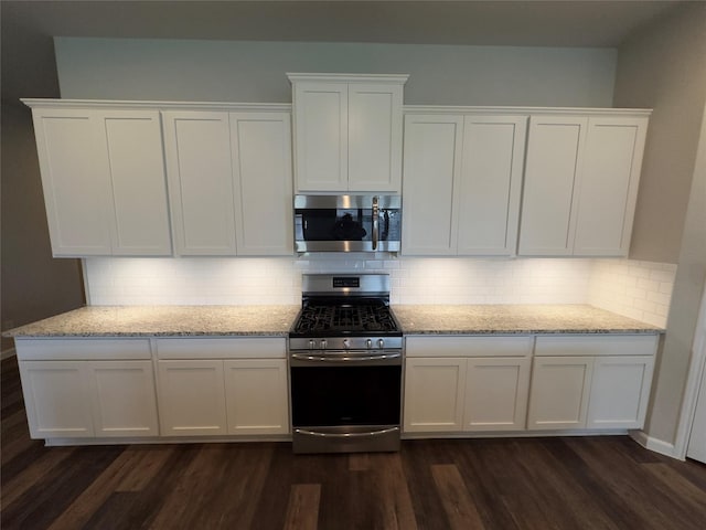 kitchen with dark wood-type flooring, white cabinets, light stone counters, and stainless steel appliances