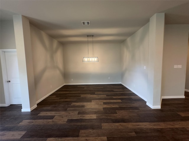 unfurnished dining area featuring dark wood finished floors, visible vents, and baseboards