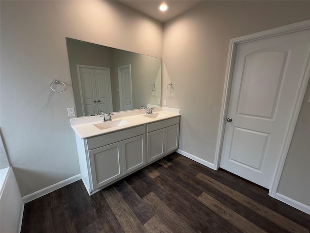 full bath with double vanity, wood finished floors, baseboards, and a sink