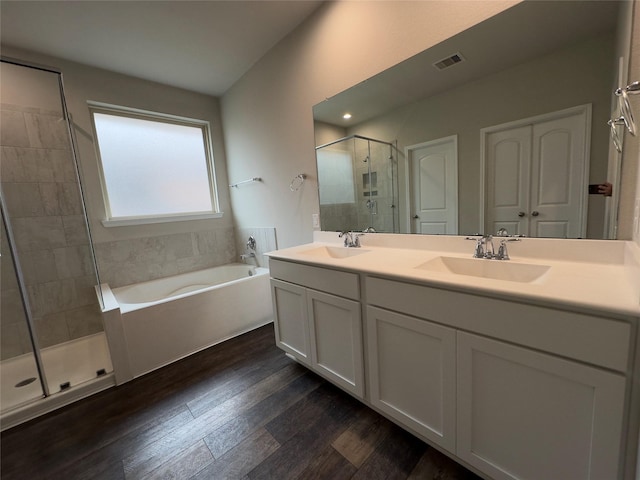 bathroom with a stall shower, wood finished floors, visible vents, and a sink