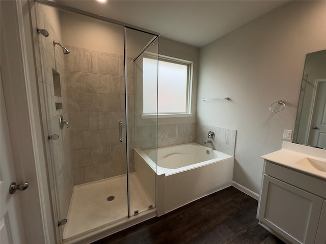 bathroom with baseboards, a stall shower, wood finished floors, a bath, and vanity