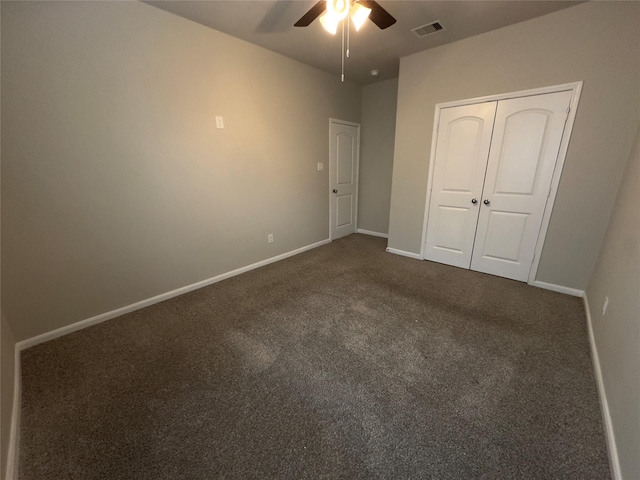 unfurnished bedroom featuring visible vents, a ceiling fan, dark carpet, a closet, and baseboards