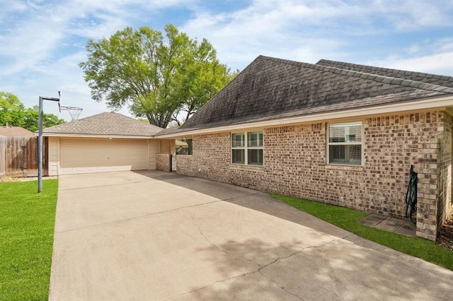 exterior space featuring brick siding, driveway, a garage, and fence