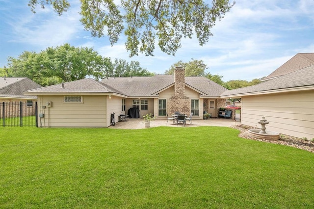 back of property with fence, a yard, a shingled roof, a chimney, and a patio area