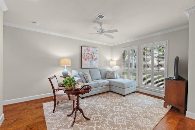 living area with visible vents, baseboards, wood finished floors, and ornamental molding