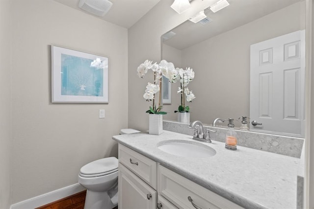 bathroom featuring visible vents, baseboards, toilet, wood finished floors, and vanity