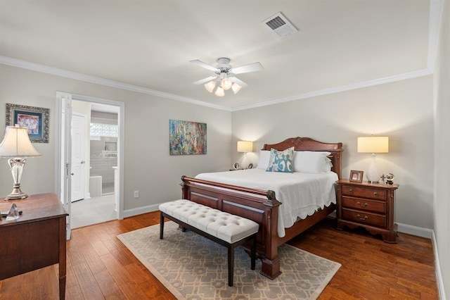 bedroom featuring visible vents, ensuite bathroom, hardwood / wood-style floors, crown molding, and baseboards