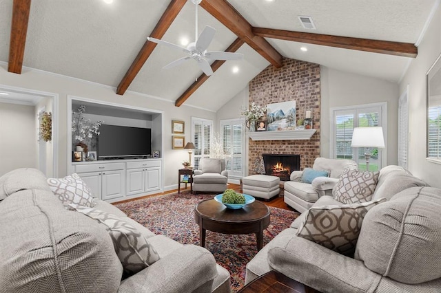 living area with a wealth of natural light, visible vents, a fireplace, and wood finished floors