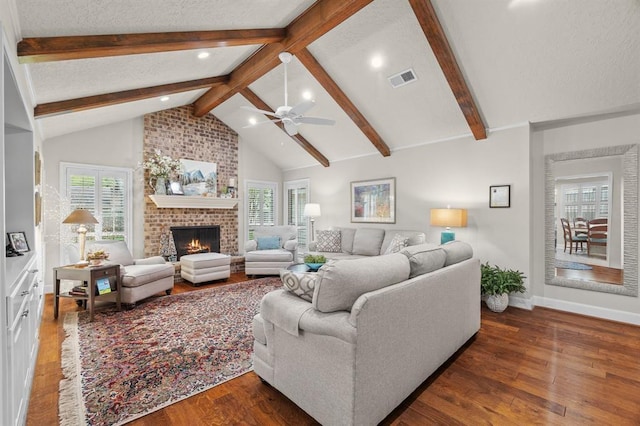 living room with a textured ceiling, a brick fireplace, and wood finished floors