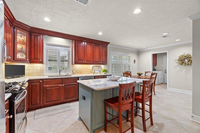 kitchen with a healthy amount of sunlight, a sink, ornamental molding, stainless steel appliances, and washer and clothes dryer