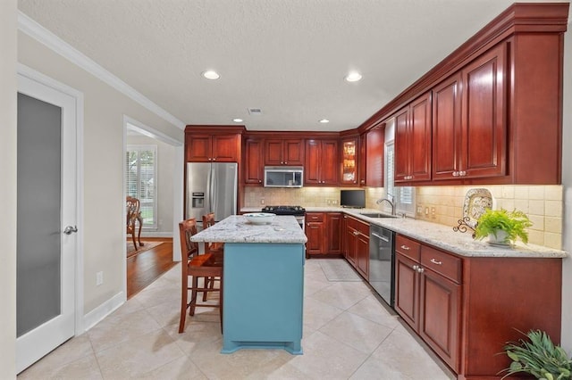 kitchen with a sink, decorative backsplash, appliances with stainless steel finishes, a kitchen bar, and a center island