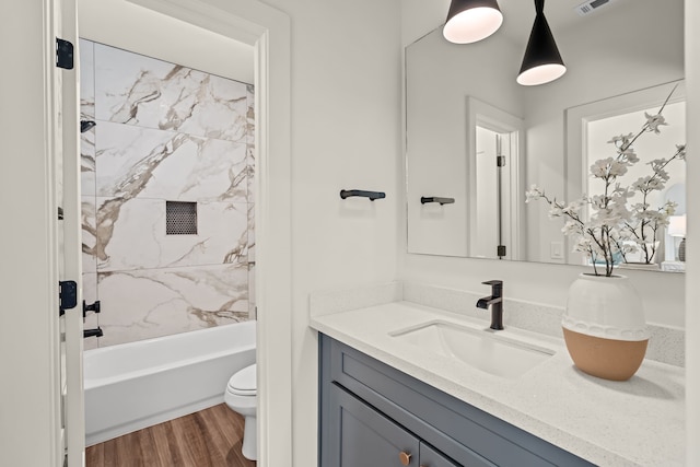 bathroom featuring vanity, wood finished floors, visible vents, shower / bathing tub combination, and toilet