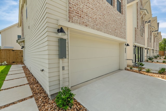 view of side of home with a garage, driveway, and fence