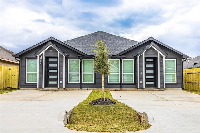 view of front of home with a shingled roof and fence