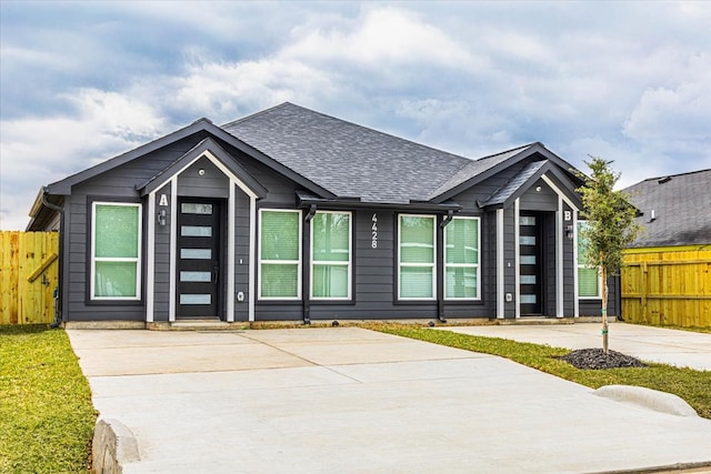 view of front of house featuring a shingled roof and fence