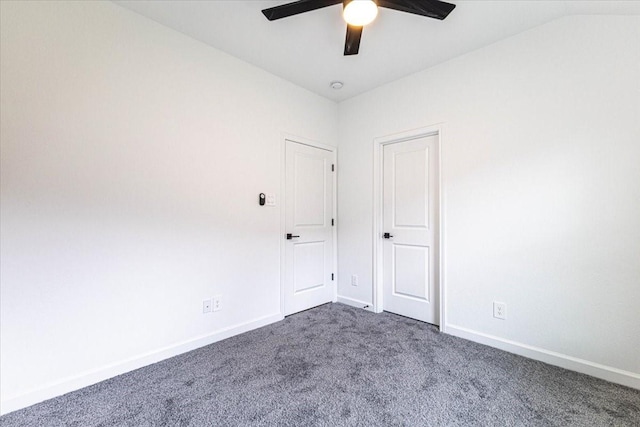 spare room featuring a ceiling fan, lofted ceiling, baseboards, and dark colored carpet