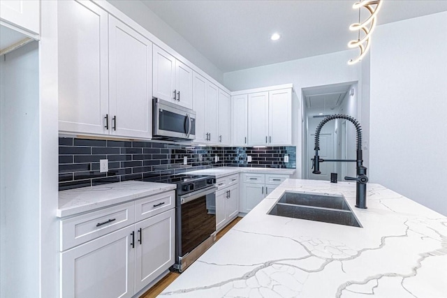 kitchen with decorative backsplash, stainless steel appliances, wood finished floors, white cabinetry, and a sink