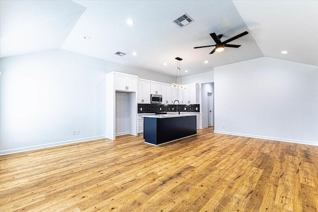 kitchen featuring open floor plan, stainless steel microwave, lofted ceiling, and visible vents