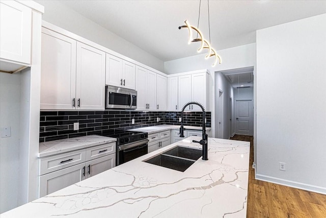 kitchen featuring stainless steel microwave, backsplash, light wood-type flooring, electric stove, and a sink