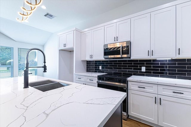 kitchen featuring visible vents, range with electric cooktop, a sink, stainless steel microwave, and tasteful backsplash