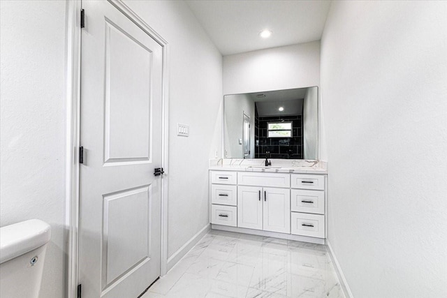 bathroom with vanity, toilet, baseboards, and marble finish floor