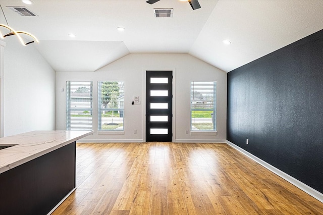 foyer with visible vents, a healthy amount of sunlight, light wood-style floors, and vaulted ceiling