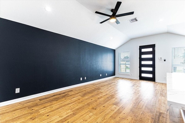 spare room featuring vaulted ceiling, wood finished floors, visible vents, and a wealth of natural light