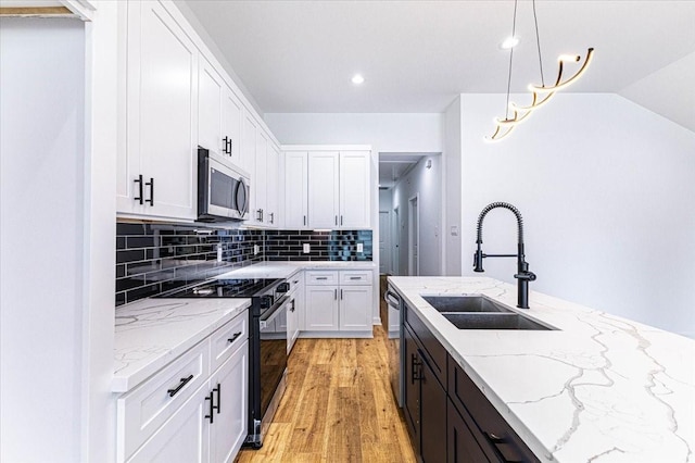 kitchen featuring white cabinetry, decorative backsplash, appliances with stainless steel finishes, and a sink