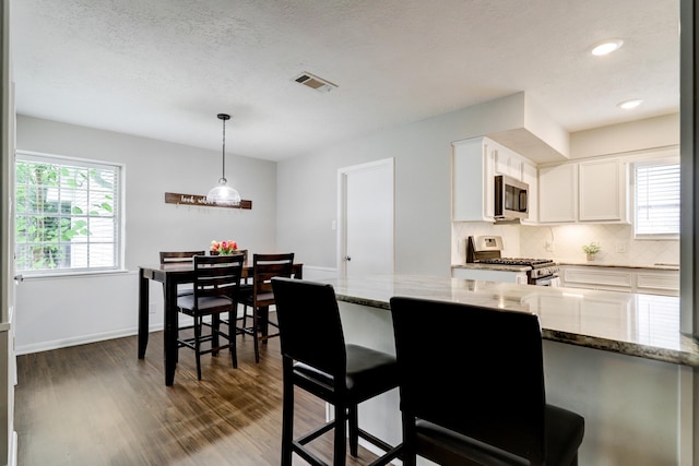 kitchen featuring dark wood-style floors, visible vents, decorative backsplash, appliances with stainless steel finishes, and white cabinetry