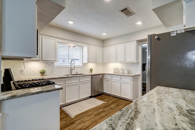 kitchen featuring visible vents, dark wood-type flooring, a sink, appliances with stainless steel finishes, and white cabinets