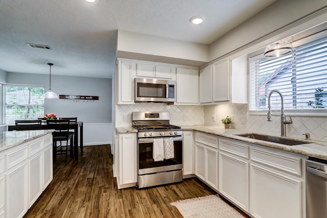 kitchen with dark wood-style floors, visible vents, a sink, appliances with stainless steel finishes, and white cabinetry