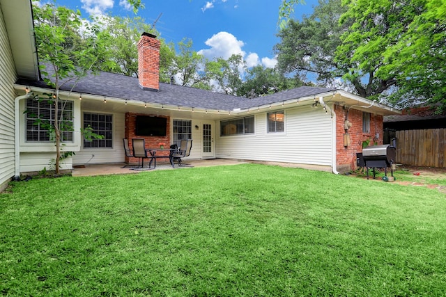 rear view of property with brick siding, fence, a lawn, a chimney, and a patio