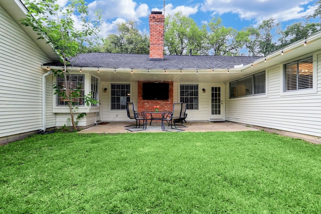 rear view of property with a shingled roof, a yard, a patio area, and a chimney