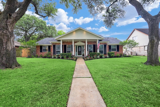 greek revival inspired property featuring a front yard, fence, and brick siding