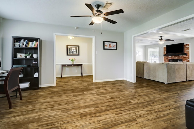 interior space with visible vents, baseboards, wood finished floors, a textured ceiling, and a ceiling fan