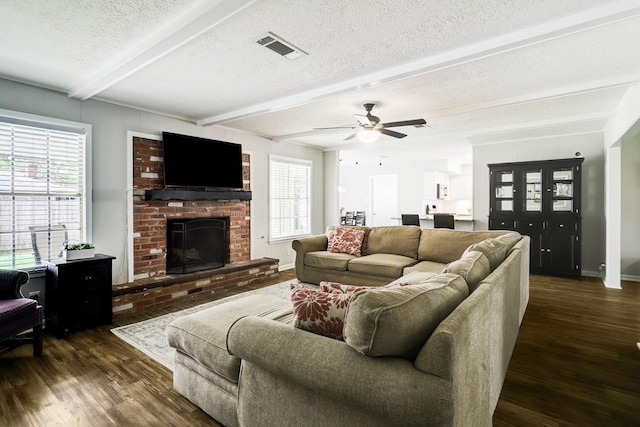 living room with beam ceiling, visible vents, dark wood finished floors, and a textured ceiling