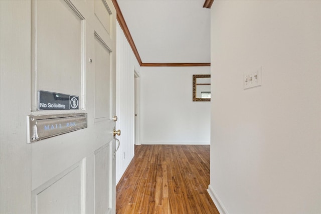 corridor featuring crown molding, baseboards, and wood finished floors