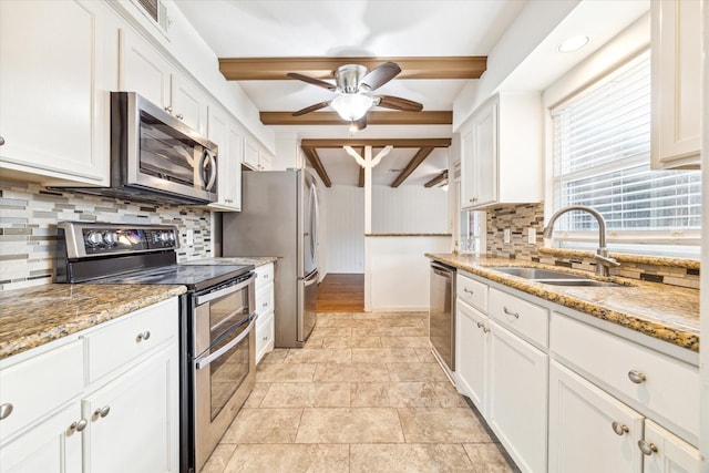 kitchen with light stone countertops, a sink, stainless steel appliances, white cabinets, and tasteful backsplash