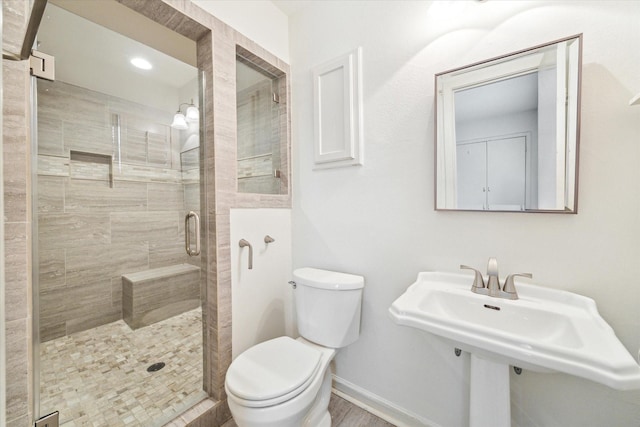 bathroom featuring a sink, baseboards, toilet, and a stall shower