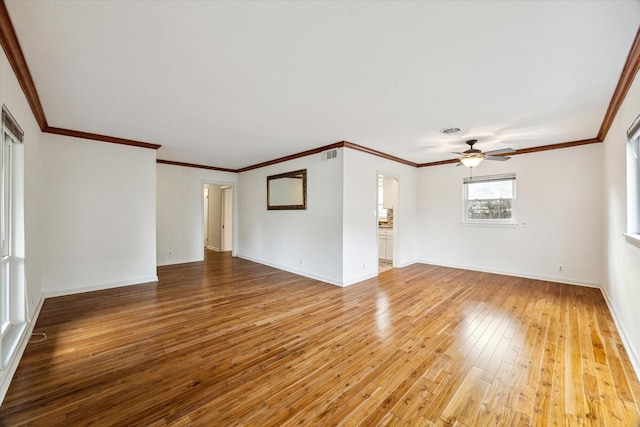 spare room featuring a ceiling fan, visible vents, baseboards, ornamental molding, and light wood-style floors