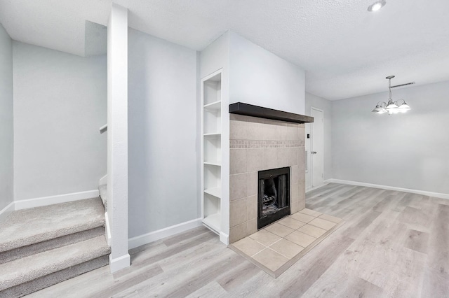 unfurnished living room featuring a fireplace, a textured ceiling, baseboards, and wood finished floors